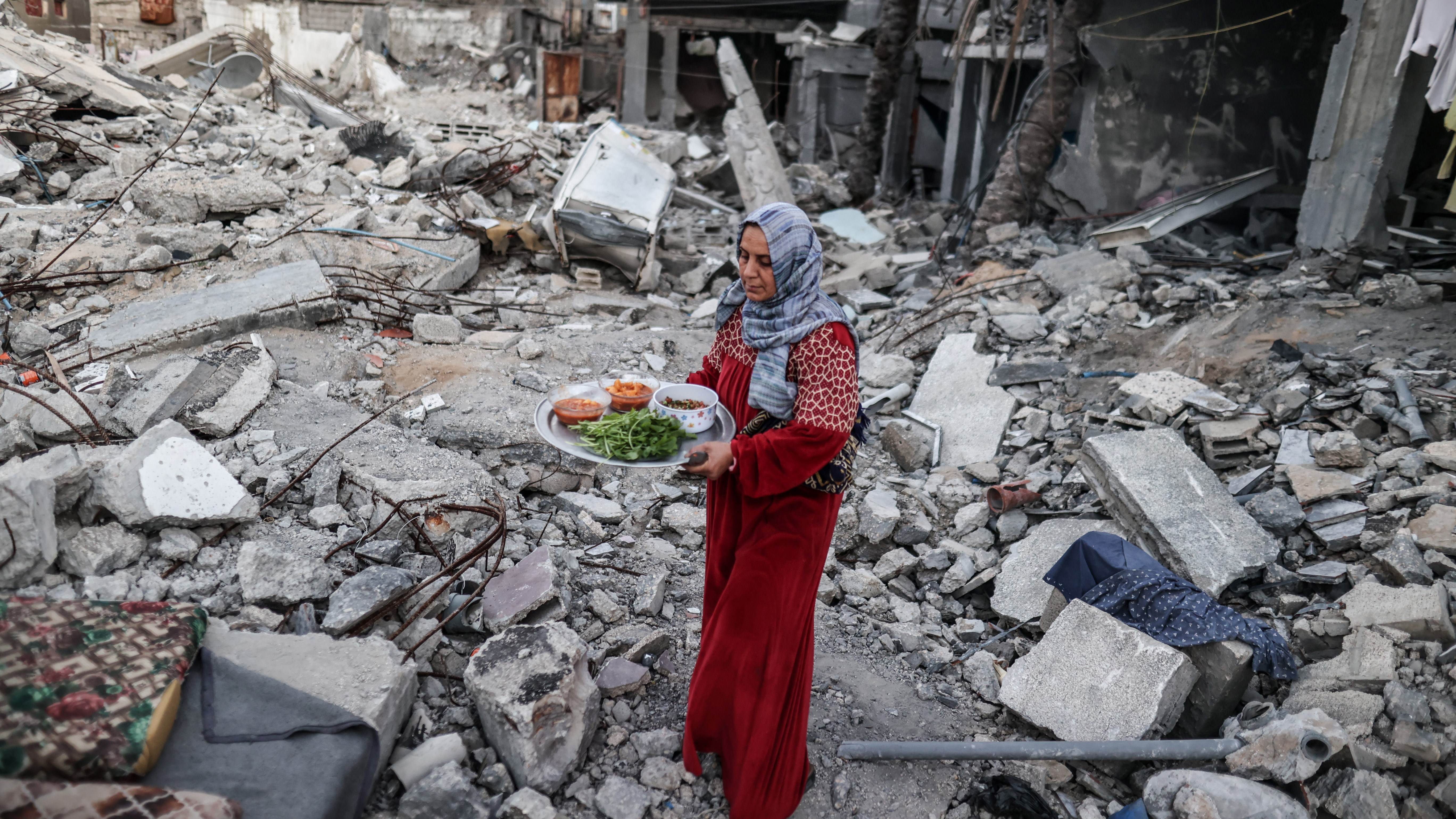 12 March 2024, Gaza. Woman having an Iftar meal during Ramadan on the rubbles of her family’s destroyed home. © WFP/Ali Jadallah