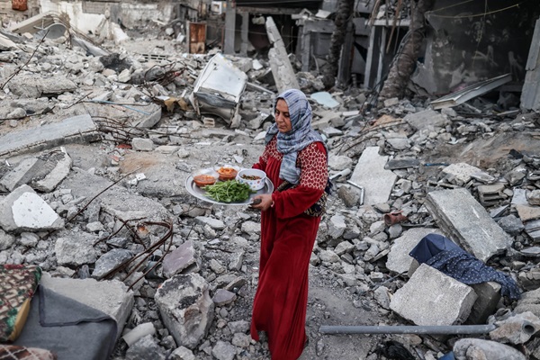 12 March 2024, Gaza. Woman having an Iftar meal during Ramadan on the rubbles of her family’s destroyed home. © WFP/Ali Jadallah